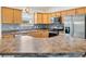 Close-up of an eat in kitchen with stainless steel appliances, wood cabinets, and tile backsplash at 3118 Sweetgum St, The Villages, FL 32163