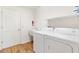 A functional laundry room boasts modern washer and dryer, utility sink, overhead storage, and durable flooring at 3118 Sweetgum St, The Villages, FL 32163