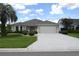 Charming single-story home with a well-manicured lawn, beautiful landscaping, and a paved driveway leading to a two-car garage at 3177 Williams Rd, The Villages, FL 32162