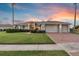 Charming home with a well-manicured lawn, brick driveway and three-car garage at dusk at 4879 Brightmour Cir, Orlando, FL 32837