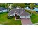 Waterfront home with a brick driveway, mature landscaping, and an attached two car garage at 4879 Brightmour Cir, Orlando, FL 32837