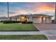 Charming home with a well-manicured lawn, brick driveway and three-car garage at dusk at 4879 Brightmour Cir, Orlando, FL 32837