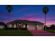 Well maintained waterfront home at dusk with a brick driveway, mature landscaping, and an attached two car garage at 4879 Brightmour Cir, Orlando, FL 32837