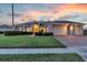 Charming home with a well-manicured lawn, brick driveway and three-car garage at dusk at 4879 Brightmour Cir, Orlando, FL 32837