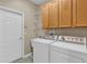 Functional laundry room featuring washer, dryer, cabinets, utility sink and tile flooring at 4879 Brightmour Cir, Orlando, FL 32837