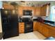 Efficient kitchen with black appliances, wood cabinets, black countertops, and bright tile flooring at 529 Del Mar Dr, Lady Lake, FL 32159