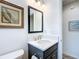 Bathroom featuring a decorative mirror, white countertop, dark cabinets, and a framed wall art piece at 6633 Holovak Ter, The Villages, FL 34762
