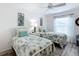 Bright bedroom featuring two twin beds, a ceiling fan, decorative lamps, and neutral colors at 6633 Holovak Ter, The Villages, FL 34762