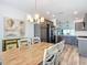 Dining area with rustic wooden table, updated chandelier, gray cabinets, and stainless steel appliances at 6633 Holovak Ter, The Villages, FL 34762
