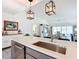 Kitchen island with stainless sink, modern pendant lights, and open view to the living room at 6633 Holovak Ter, The Villages, FL 34762