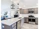 Modern kitchen featuring gray cabinets, stainless steel appliances, a white countertop, and an island with a sink at 6633 Holovak Ter, The Villages, FL 34762
