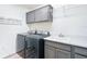 Functional laundry room with washer, dryer, sink, gray cabinets, and practical shelving at 6633 Holovak Ter, The Villages, FL 34762