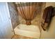 This bathroom showcases a bathtub with tan tile surround, a decorative shower curtain, and a towel rack with plush brown towels at 664 Mission Hills Trl, The Villages, FL 32162