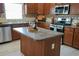 Kitchen island with bar, stainless appliances, tile backsplash, and lots of counter space at 664 Mission Hills Trl, The Villages, FL 32162