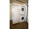A stacked washer and dryer unit is in a garage with a refrigerator at 664 Mission Hills Trl, The Villages, FL 32162