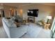 Bright living room has gray sofa and chairs, side tables, area rug and mounted flatscreen television at 664 Mission Hills Trl, The Villages, FL 32162