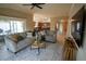 Open-concept living room with wood floors and comfortable gray couches, flowing into the kitchen at 664 Mission Hills Trl, The Villages, FL 32162