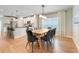 Open concept with a dining room featuring wood floors, a long wood table, and black dining chairs, and the kitchen is in the background at 678 Blackstone St, Minneola, FL 34715