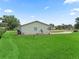 Large green backyard features manicured lawn, mature trees, and exterior of the house at 71 Stone Haven Ct, Leesburg, FL 34788