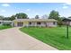 The front of a single-story home with a well-manicured lawn and a long driveway at 71 Stone Haven Ct, Leesburg, FL 34788