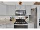 Modern kitchen featuring stainless steel appliances and grey cabinets with light granite countertops at 8635 Se 156 St, Summerfield, FL 34491