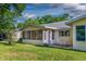 Spacious backyard with a sunroom extension and a patio area, surrounded by green lawn and mature trees at 8738 Sw 95Th Ln # B, Ocala, FL 34481