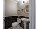 Elegant powder room featuring a pedestal sink and stylish black tile accent wall at 8738 Sw 95Th Ln # B, Ocala, FL 34481