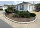 Charming home exterior with a well-maintained landscaped yard featuring a palm tree and lush shrubs at 8932 Se 168Th Sedgwick Pl, The Villages, FL 32162