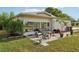 Back patio featuring outdoor seating, lush landscaping, and a beautiful garden view under a bright sky at 1 Aberdeen Cir, Leesburg, FL 34788
