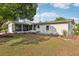 A green backyard featuring a screened lanai, lawn, and garden bed at 1 Aberdeen Cir, Leesburg, FL 34788