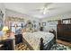 Cozy bedroom with floral bedding, curtains, wood furnishings, and overhead ceiling fan at 1 Aberdeen Cir, Leesburg, FL 34788