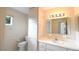 Well-lit bathroom featuring a vanity, a toilet with a built-in cabinet, and a large mirror at 10442 Se 179Th Pl, Summerfield, FL 34491