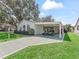 Inviting single story home featuring a covered carport, a beautifully manicured lawn, and mature trees at 1202 Del Toro Dr, Lady Lake, FL 32159