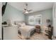 Cozy bedroom with a neutral color scheme, ceiling fan, and a window overlooking the yard at 12401 Blue Heron Way, Leesburg, FL 34788