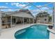 Backyard pool area boasts a covered patio, pool, and a view of the surrounding landscaping at 12401 Blue Heron Way, Leesburg, FL 34788