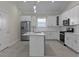 Modern kitchen with stainless steel appliances, island with sink, white cabinets, and pendant lights at 12624 Ne 49Th Dr, Oxford, FL 34484