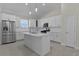 Modern kitchen with stainless steel appliances, island with sink, white cabinets, and pendant lights at 12624 Ne 49Th Dr, Oxford, FL 34484