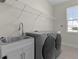 Laundry room with modern washer and dryer and stainless steel sink at 12624 Ne 49Th Dr, Oxford, FL 34484