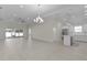 Spacious open-concept living area with bright white floors, modern lighting, kitchen, and sliding glass doors at 12624 Ne 49Th Dr, Oxford, FL 34484