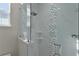 Shower with decorative accent tiles, shelving, and a glass door at 12624 Ne 49Th Dr, Oxford, FL 34484
