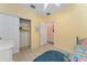 Bright bedroom with closet, yellow walls, ceiling fan, and blue area rug on tile floor at 12687 Se 90Th Ter, Summerfield, FL 34491
