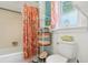 Bright bathroom featuring a white tub with a floral shower curtain and modern shelving for towel storage at 1301 North Ave, Tavares, FL 32778