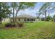 Spacious backyard with lush green lawn, mature trees, and exterior of the sunroom at 13050 Se 89Th Cir, Summerfield, FL 34491
