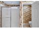 Shower with glass doors and commode shown against floral wallpaper at 13050 Se 89Th Cir, Summerfield, FL 34491