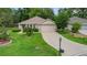 Single-story home with a two-car garage, complemented by well-manicured lawn and a long driveway at 13050 Se 89Th Cir, Summerfield, FL 34491
