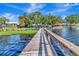 View of the wooden dock extending over the tranquil water towards residential homes at 1341 W Lakeshore Dr, Clermont, FL 34711