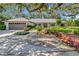Inviting single-story home featuring mature landscaping, a two-car garage, and a charming red front door at 1341 W Lakeshore Dr, Clermont, FL 34711