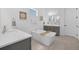 This bright white bathroom features a soaking tub, gray vanity, neutral decor and wood-look floors at 14513 Winter Stay Dr, Winter Garden, FL 34787