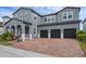 Gray two-story home featuring a brick driveway leading to a three-car garage at 14513 Winter Stay Dr, Winter Garden, FL 34787