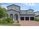 Two-story gray home featuring a brick driveway, a three-car garage, and beautiful landscaping at 14513 Winter Stay Dr, Winter Garden, FL 34787